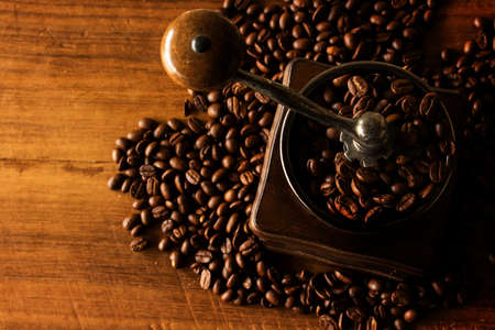 antique coffee grinder with coffee beans in the blurred background.の写真素材