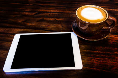 digital tablet and coffee cup on wooden tableの写真素材