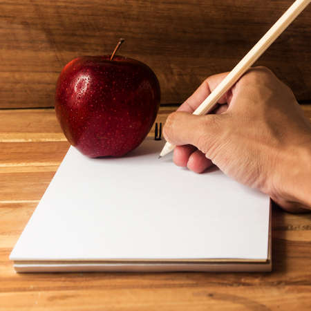 Hand writing and Fresh apple with drops of water on deaskの写真素材