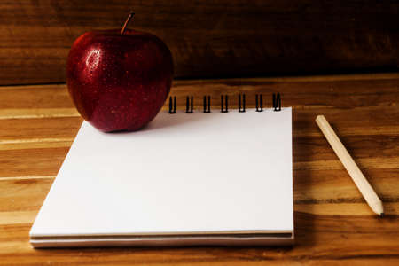 Fresh apple with drops of water,paper and pencil on wood table 