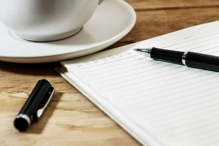 Close up open a blank white notebook, pen and cup of coffee on the deskの写真素材
