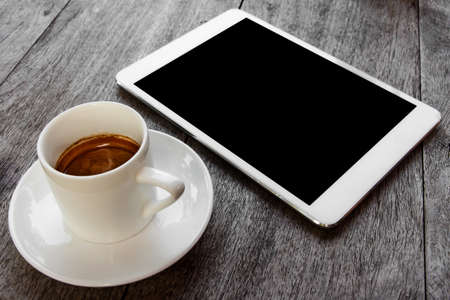 digital white tablet and coffee cup on wooden table の写真素材