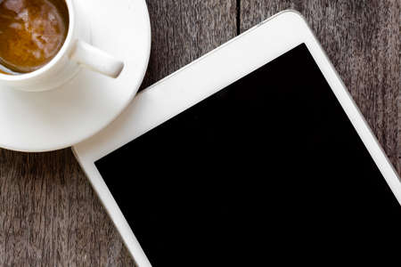 digital white tablet and coffee cup on wooden table の写真素材