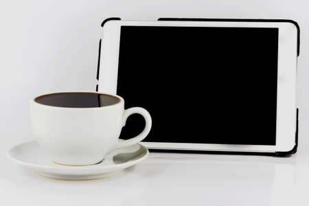Tablet computer with white cup of coffee isolated on white background.