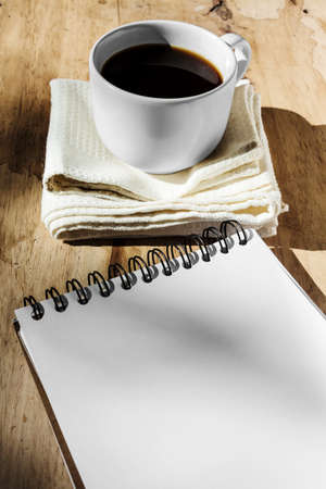 Sketchbook and instant coffee in white cup against wood backgroundの写真素材
