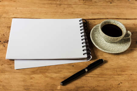 work desk with paper, pen and cup of instant coffee