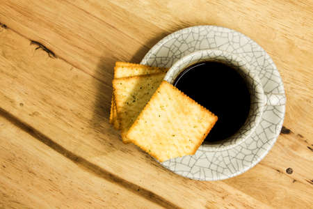 Cup of coffee with crackers on wood table.の写真素材