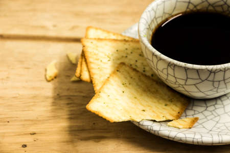 Cup of coffee with crackers on wood table.の写真素材