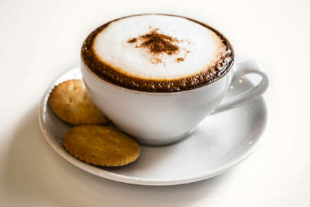 Coffee cup and cracker on white tableの写真素材