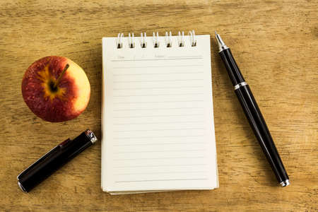 Education and idea concept.Paper sheet,pen and fresh red apple on wood tableの写真素材