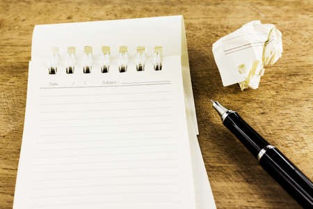 Blank notepad and crumpled with pen on wooden desk