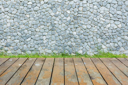 Stone wall and green grass on wood floor backgroundの写真素材