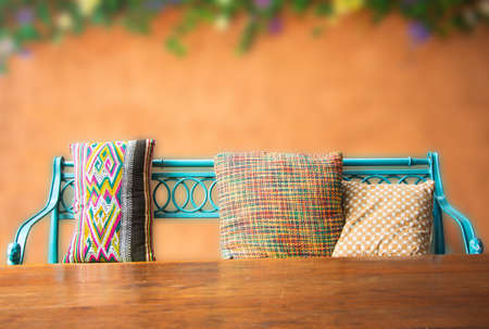 close up wooden bench against orange concrete wall decorated with floral painting.(Blurry background)の写真素材
