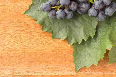 Empty space on wooden background with leaf and fresh grapeの写真素材