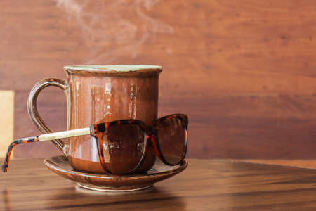 Coffee mug with sunglasses on tableの写真素材