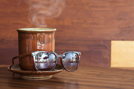 Coffee mug with sunglasses on tableの写真素材