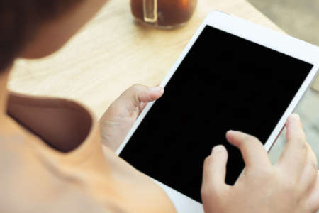 Woman using tablet computer and drinking coffee. Focus on tablet.の写真素材