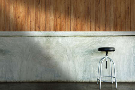 Elegant chair or stool in an empty concrete room with shadow from left side.の写真素材