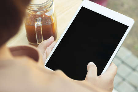 Woman using tablet computer and drinking coffee. Focus on tablet.の写真素材