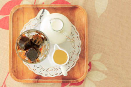 Iced coffee cube with fresh milk and syrup on tablecloth with copy space.  Selective focus top view.