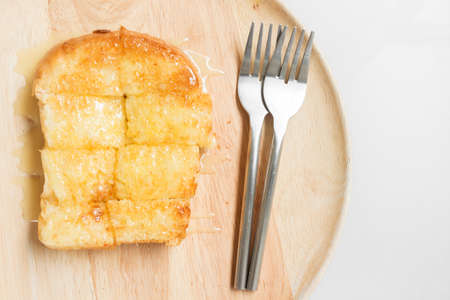 Bread toast with butter and condensed milk in wood plate.