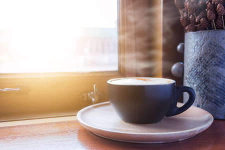 Cup of coffee with steam on table in cafeの写真素材