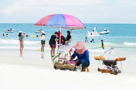 Rayong, THAILAND - May 10 : The hawker is selling somtum and grilled chicken, tourists are swimming and photographing happily on Sai-Kaew beach at Koh Samed May 10,2017 in Rayong, Thailandのeditorial素材