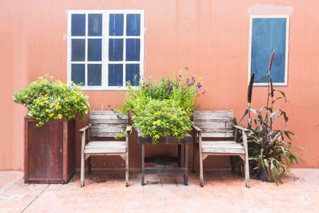 Wooden chair with flower against orange concrete background.の写真素材