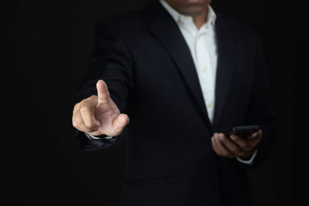 Businessman using smart phone and touching screen on black background with copy space.の写真素材