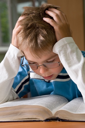 boy reading a book with hands on head の写真素材