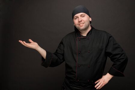 attractive chef in black uniforms gesture inviting enterの写真素材