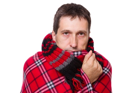 man wrapped in a warm blanket and scarf  shivering from the cold on white backgroundの写真素材