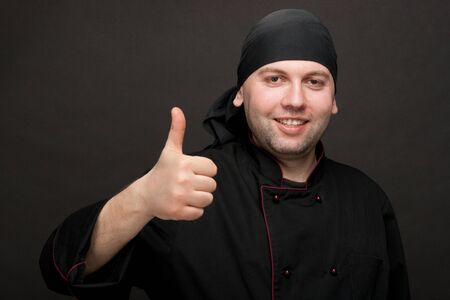 professional chef in black uniforms showing thumbs upの写真素材