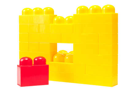 wall from yellow plastic building blocks with red  building block, ready to place into yellow onesの写真素材
