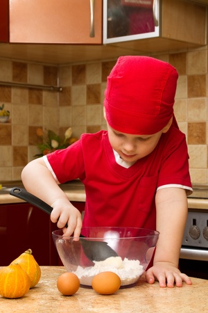 Small boy helping at kitchen with baking a pie, little chefの写真素材