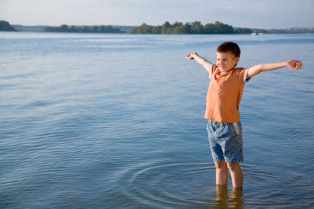 Small boy with lifted hands on beach, freedomの写真素材