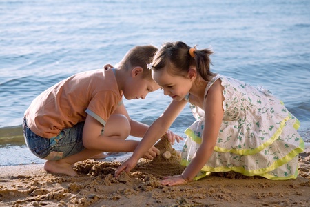 Cute little boy and girl playing in sand on beachの写真素材