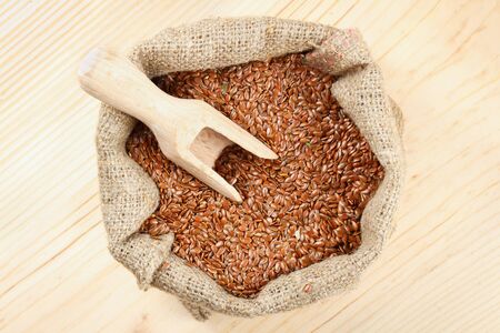 linseed, flax seeds with wooden scoop in sacking bag on wooden table, top viewの写真素材