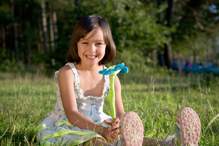 little girl sits with flower  on green grassの写真素材
