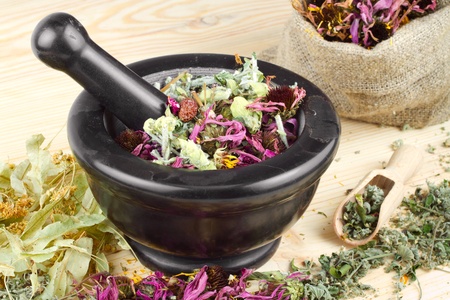 mortar and pestle and sack with healing herbs on wooden tableの写真素材
