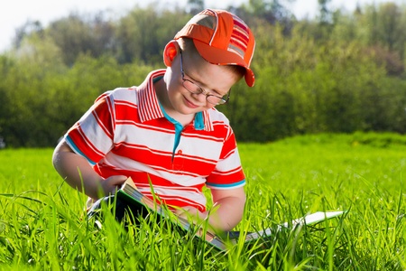 Young boy in glasses reads book in outdoor parkの写真素材
