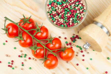 cherry tomatoes with pepper grain on wooden chopping boardの写真素材
