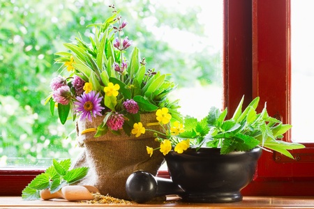 sack with bouquet of healing herbs and flowers, mortar and pestle on windowsillの写真素材