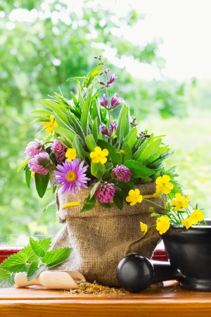 sack with bouquet of healing herbs and flowers, mortar and pestle on windowsillの写真素材
