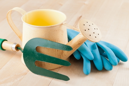 Gardening tools watering can, garden fork, rubber gloves on wooden backgroundの写真素材