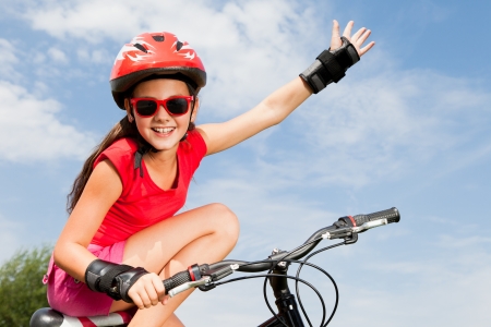 teenage girl on a bicycle with hand upの写真素材
