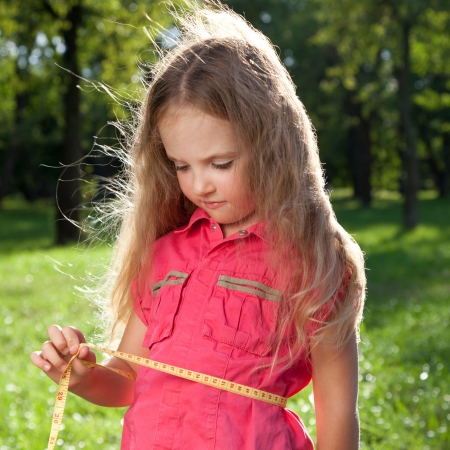 little girl measuring her her waistlineの写真素材