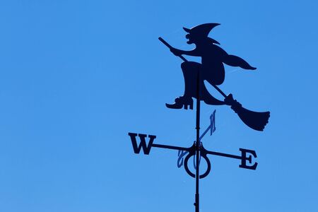 Witch on broomstick weather vane on blue sky backgroundの写真素材