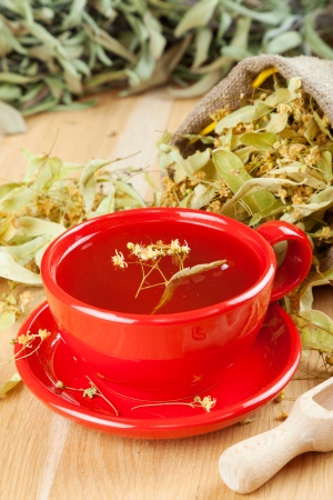 cup of linden tea and flowers in canvas bag on wooden tableの写真素材
