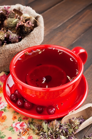 red tea cup, healing herbs on kitchen tableの写真素材